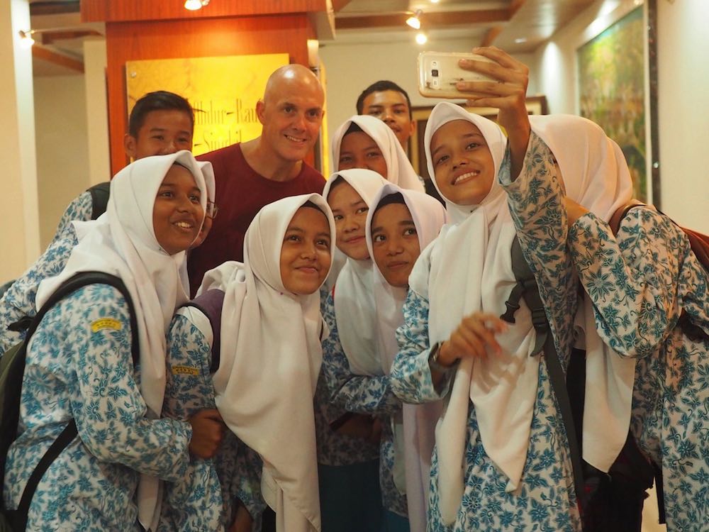 Ian having a photograph taken with a group of students Inside the Banda Aceh Museum