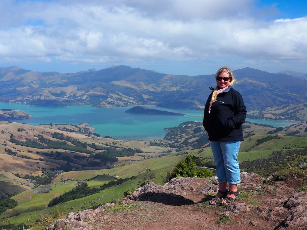 Nicky standing next to a view of Akaroa