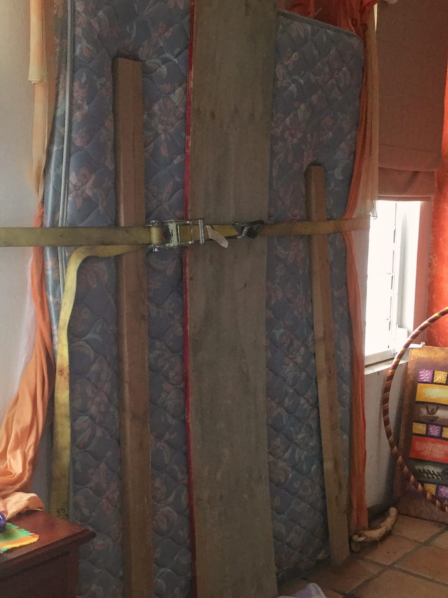 Patio doors boarded up with mattress