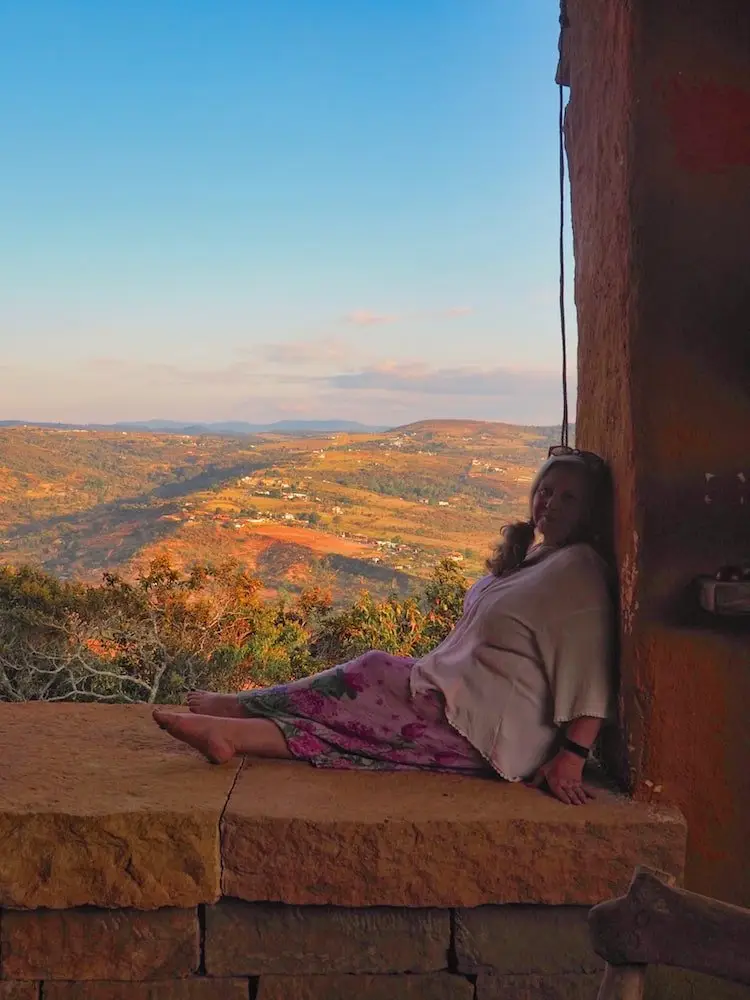 Nicky sitting on a wall with a view of the countryside behind