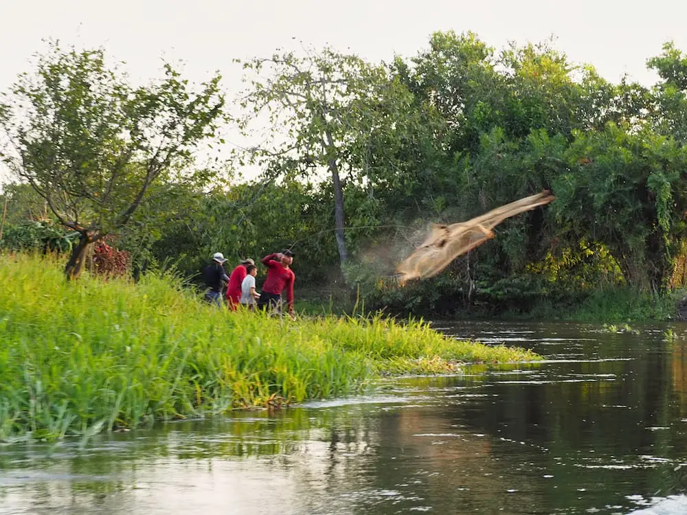 Fishermen throw a net into the river