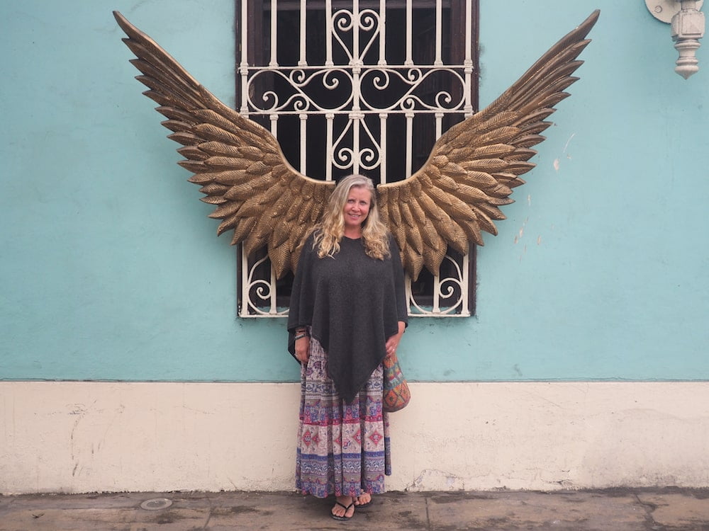 Nicky standing in front of a pair of brass wings, Barranco