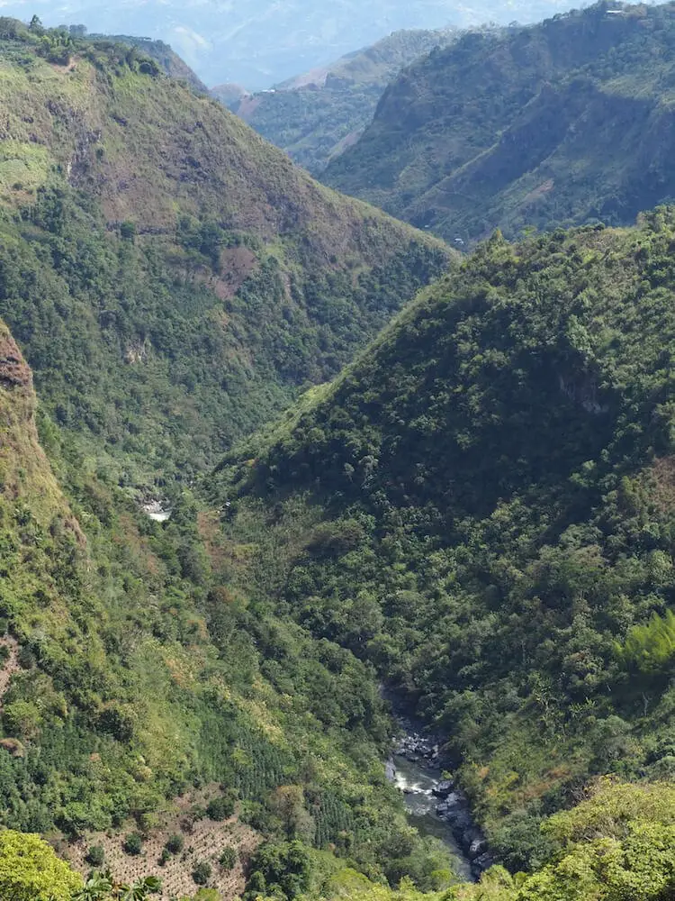 Forested hillsides descending into a valley with a river at the bottom