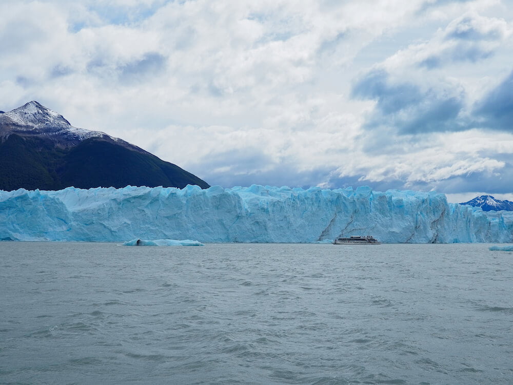 A tour boat passes close to the glacier wall