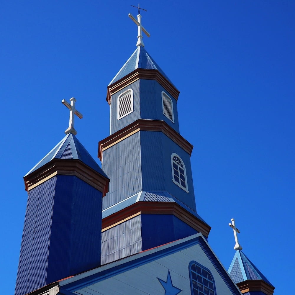 Blue wooden spires of a church against a blue sky