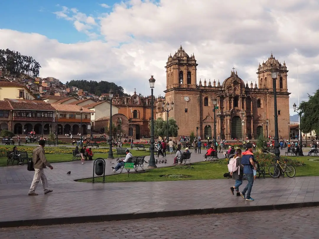 People walking along a plaza with a cathedral in the background