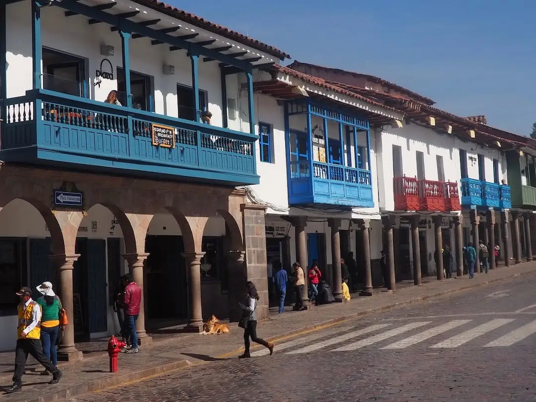A row of old buildings with blue, red and grey balconies looking over an archway