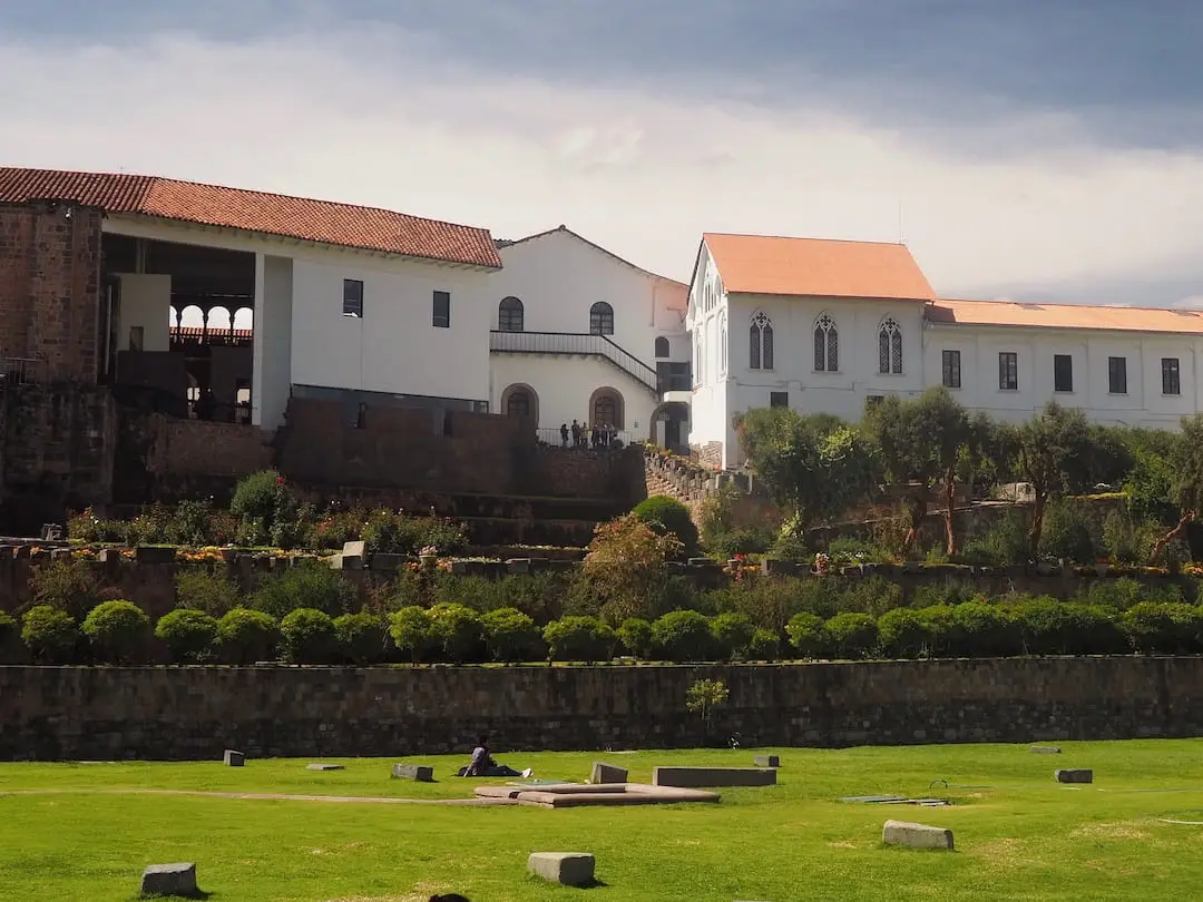 A grassy area in the foreground and a white building with red roof in the background