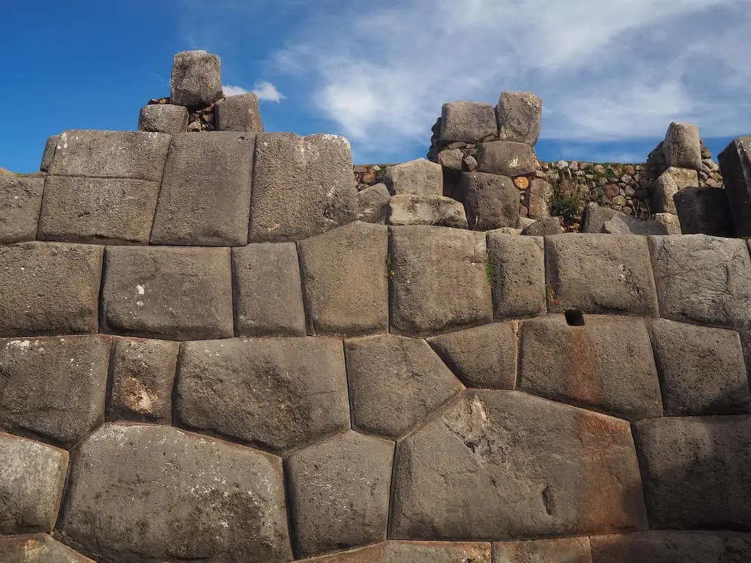 A wall constructed with irregularly shaped stones under a blue sky