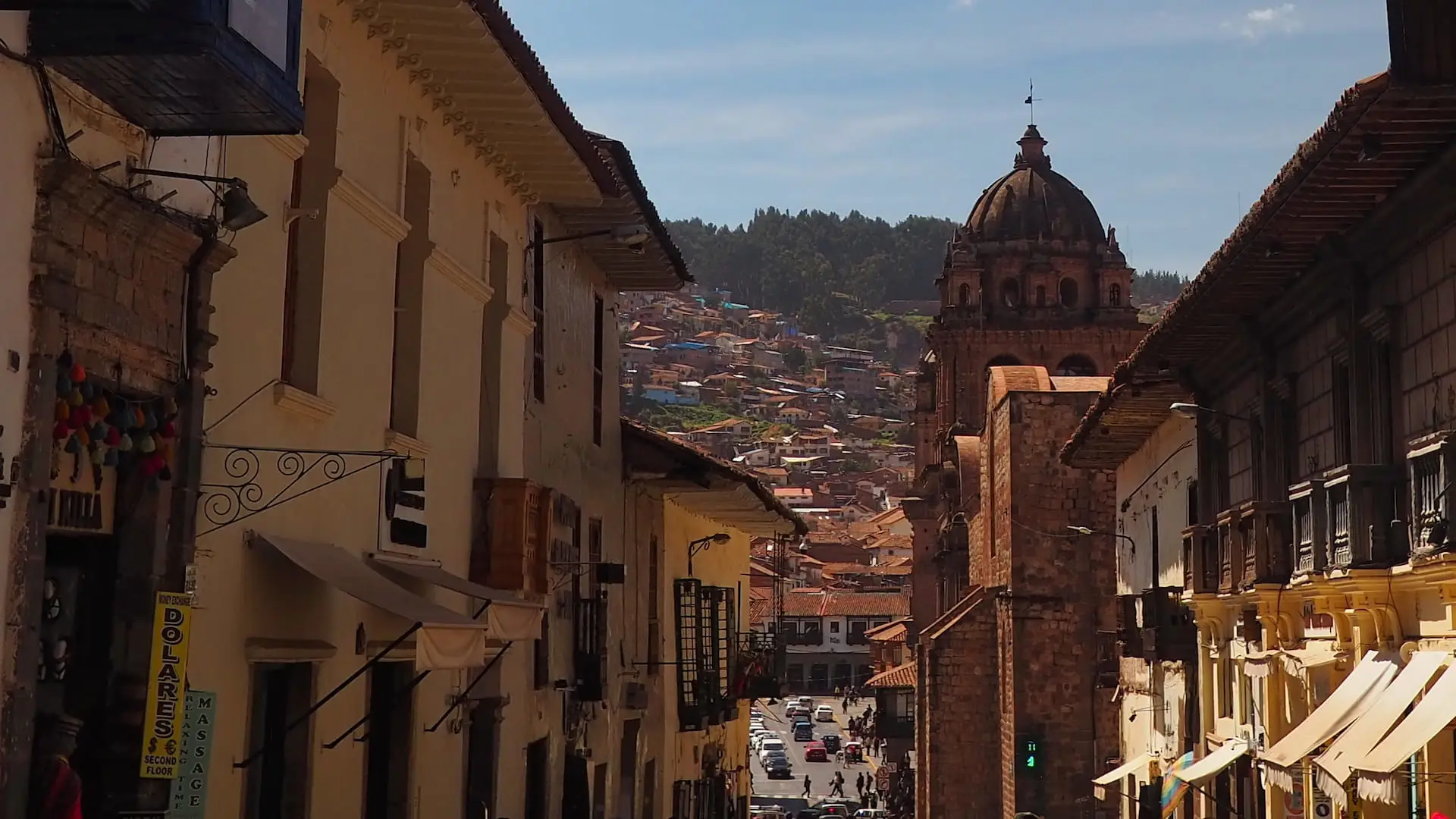 A narrow shopping street with a church on the right and red roofed houses in the background