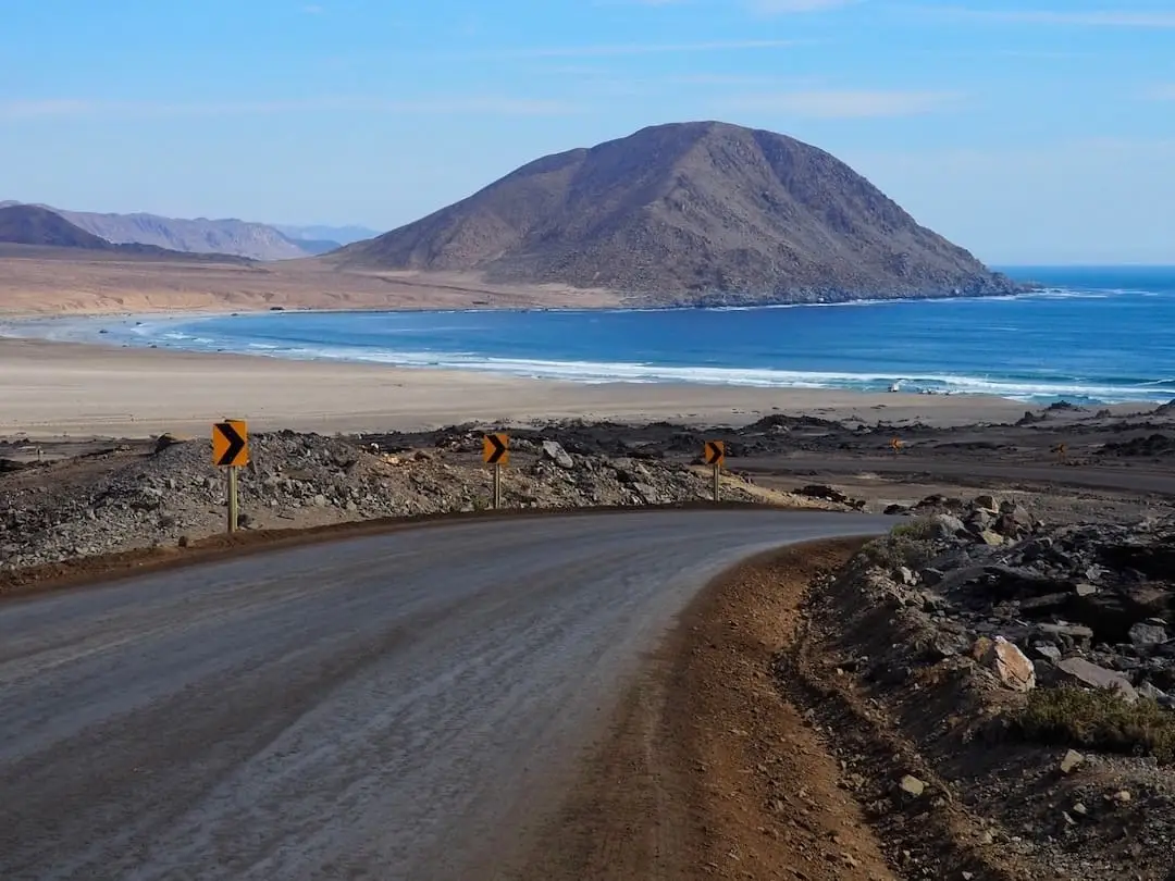 A road leads to a beach with a "sugar loaf" hill in the background