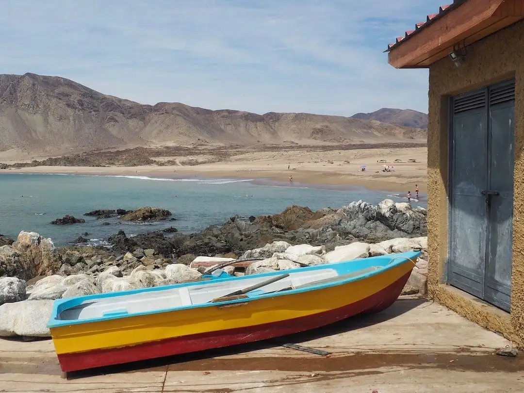 A rowing boat is parked outside a shed