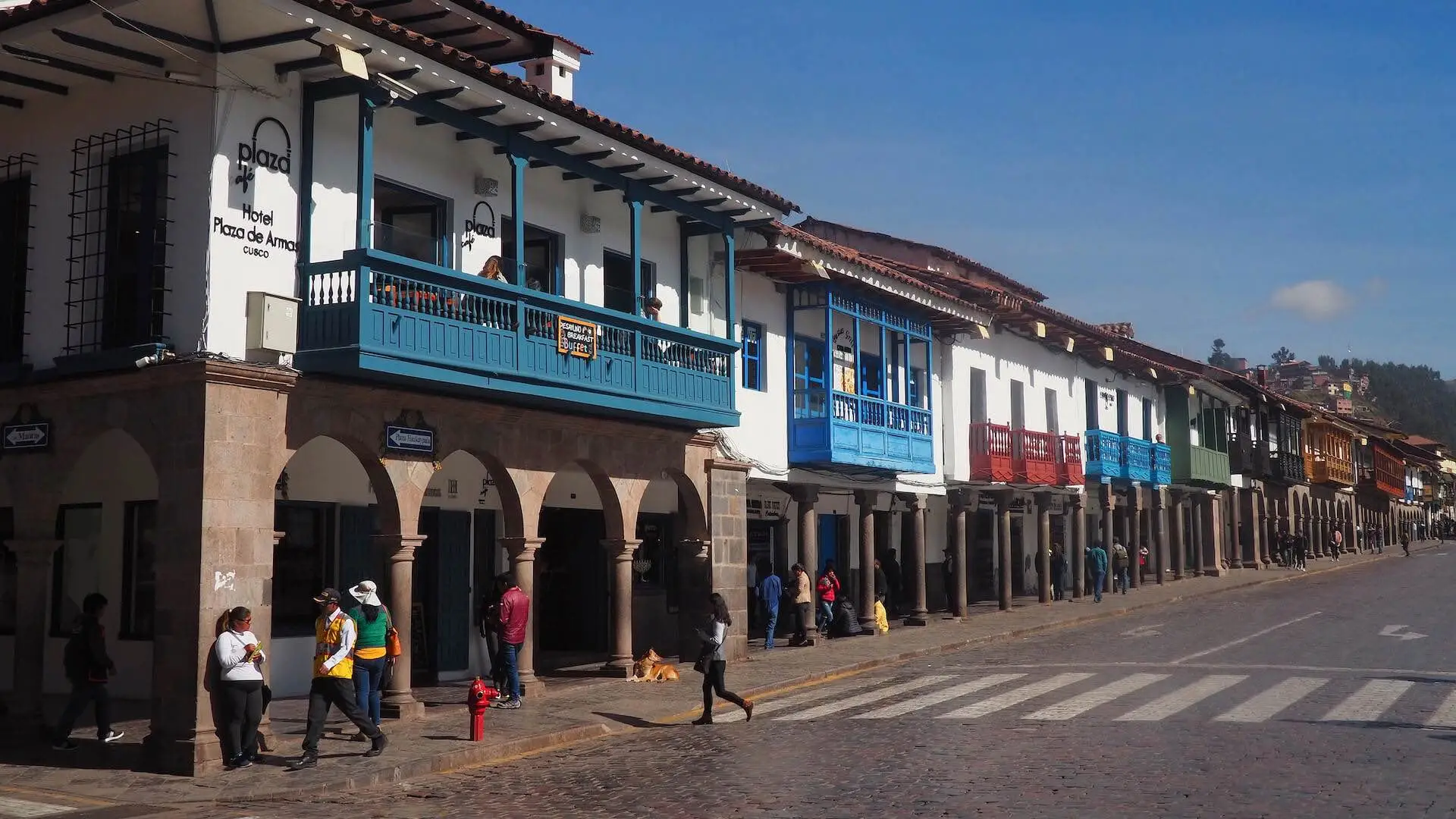 A row of old buildings with blue, red and grey balconies looking over an archway