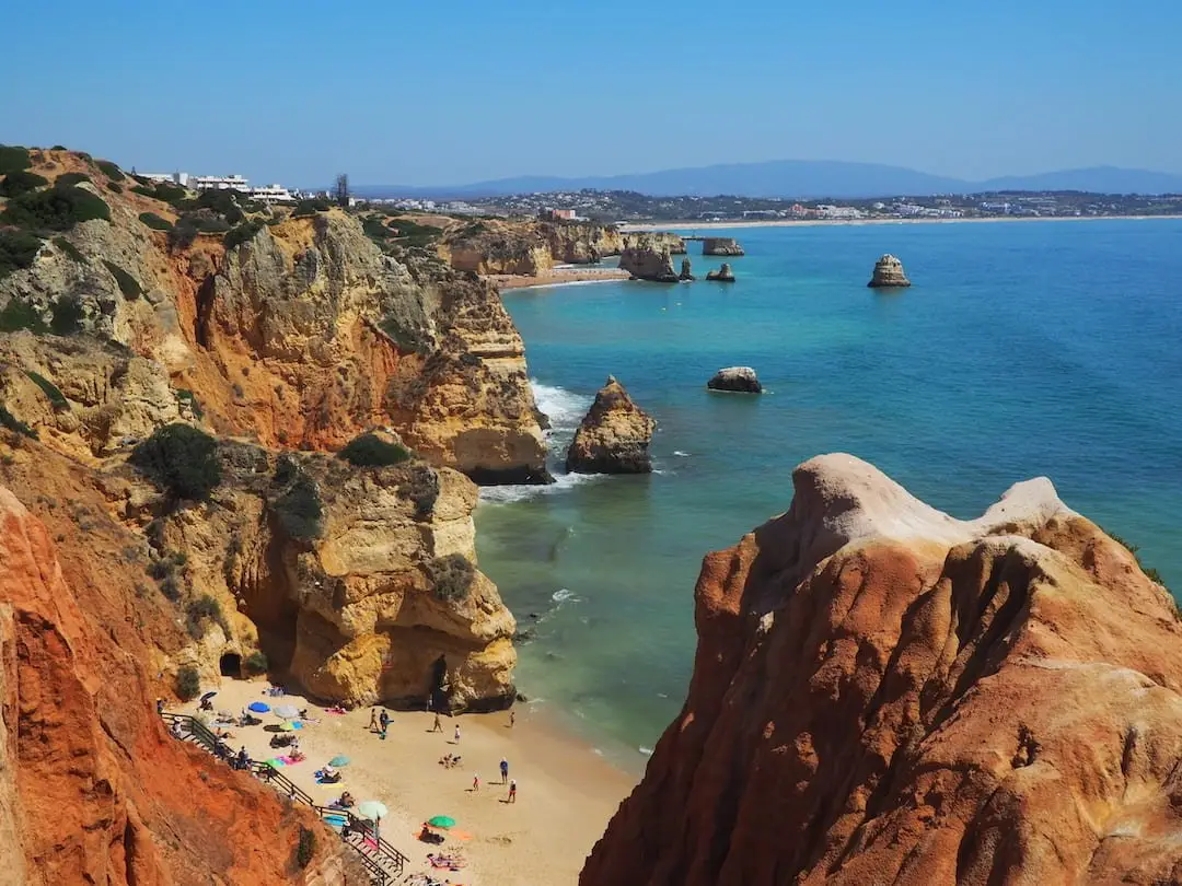 Praia Do Camilo, Lagos Umbrellas on a golden sand beach surrounded by sandstone cliffs