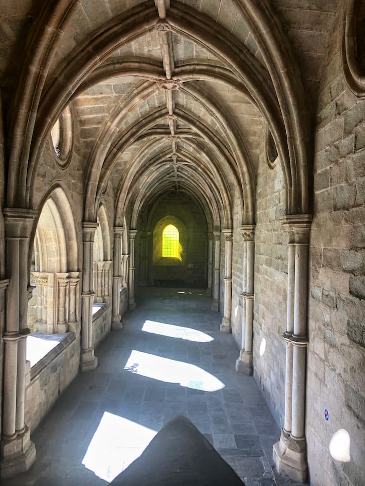 And old stone arched passageway with a yellow tinted oval window in the background