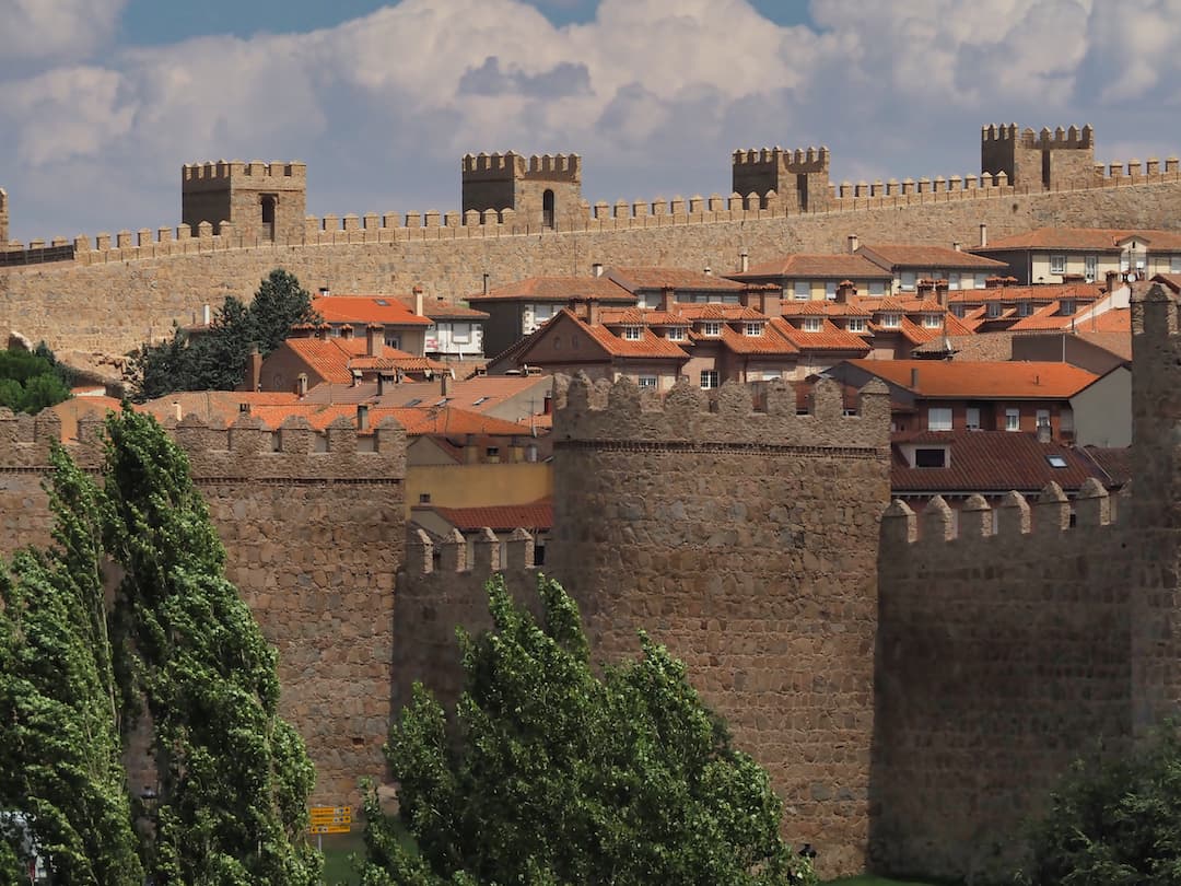 A wall with turrets surrounding red-roofed buildings