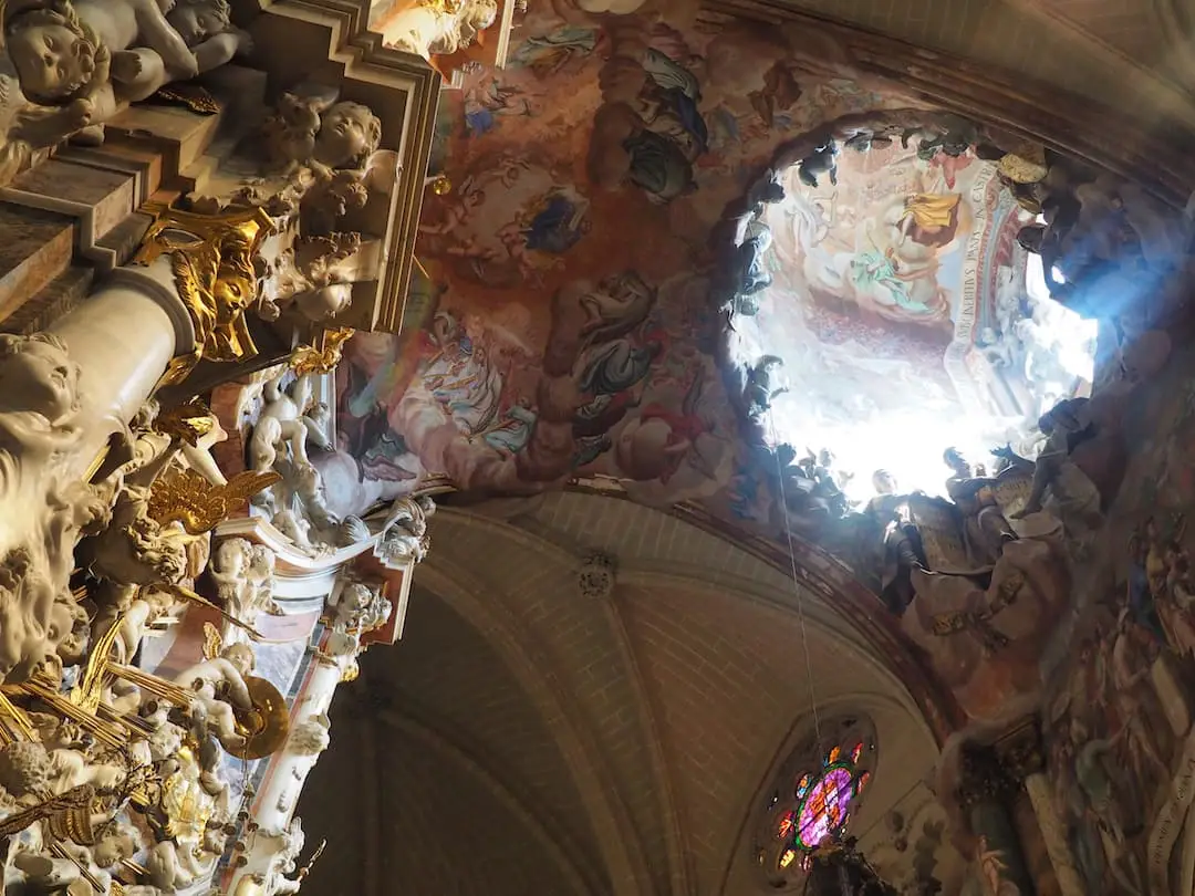Day Trips from Madrid - Toledo. A ceiling fresco painting is illuminated by light shining through a dome above