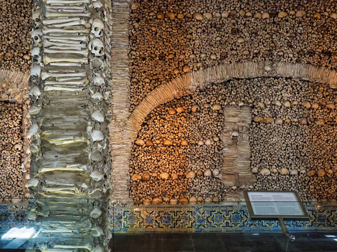 A pillar "decorated" with bones stands in front of a wall of bones