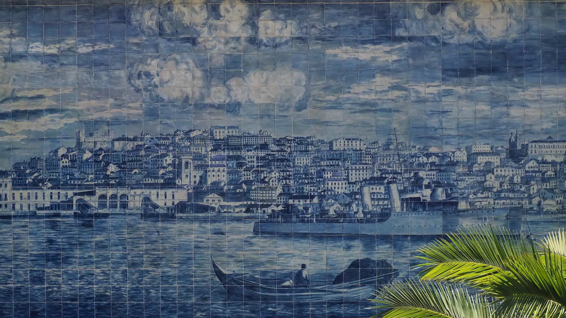A vintage depiction of Lisbon on a collage of blue tiles with green leaves to the bottom right