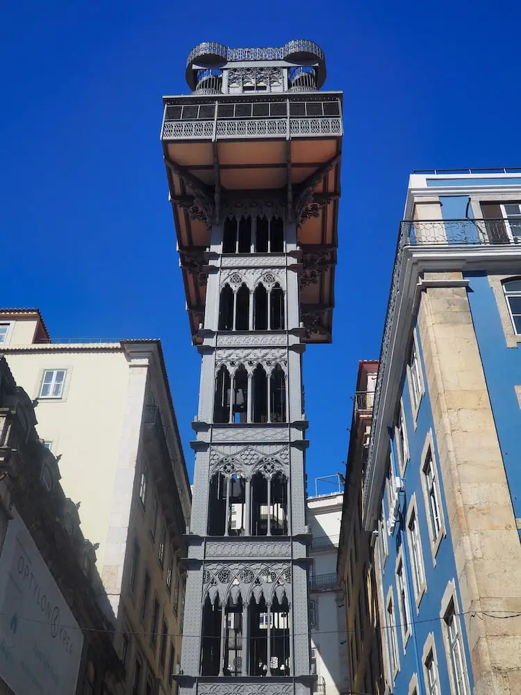 A tall metal structure with a platform on top rises between two buildings