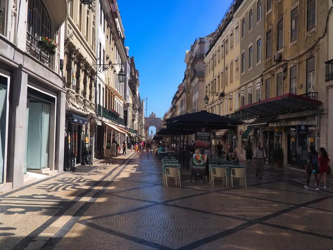 An empty paved street with an arch at the far end
