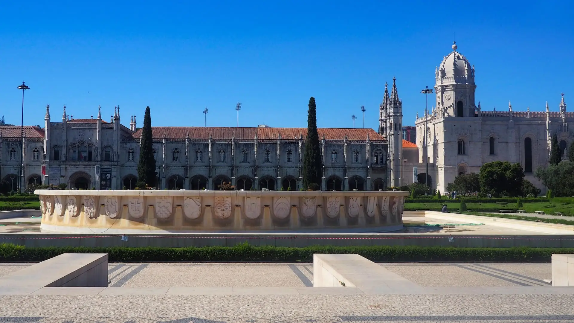 A circular fountain stands in front of a large gothic building