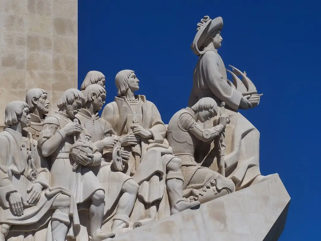 A collection of statues look out to sea from left to right