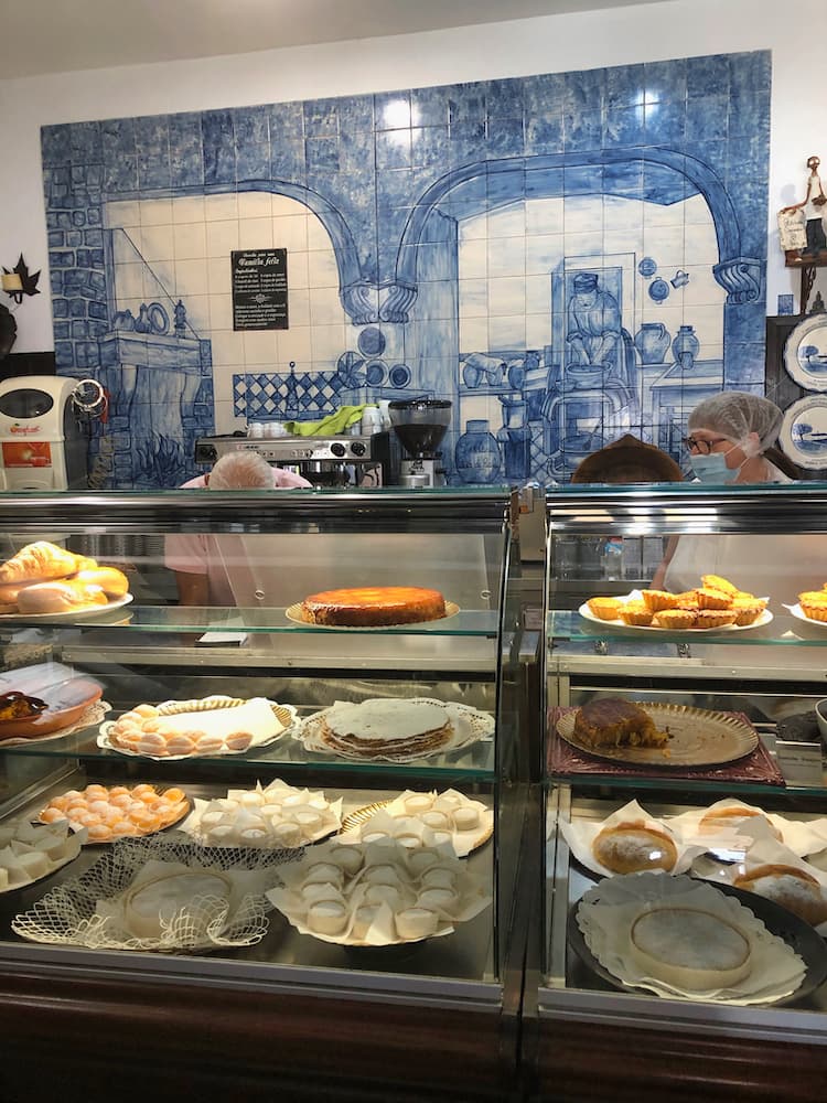 Interior of †he cafe with blue tiles on the back wall and assorted pastries in a display cabinet