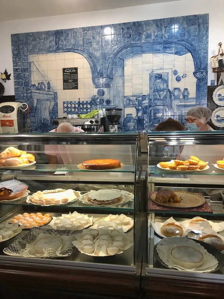 Interior of †he cafe with blue tiles on the back wall and assorted pastries in a display cabinet