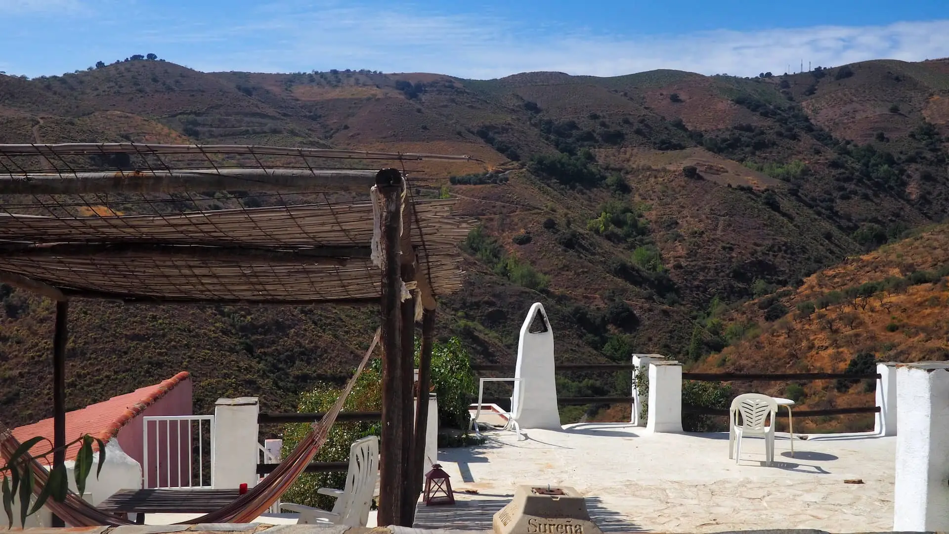A hammock and seating area in the foreground with views of fields and mountains in the background