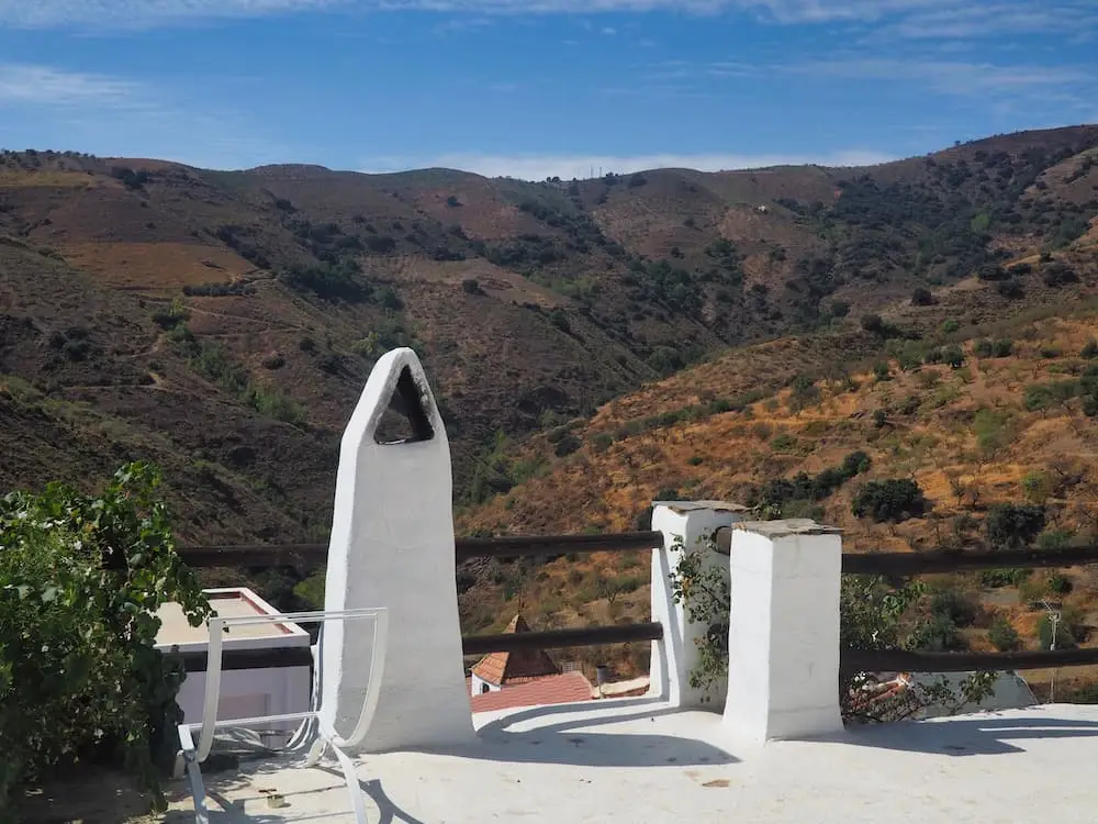 A seating area in the foreground with views of fields and mountains in the background