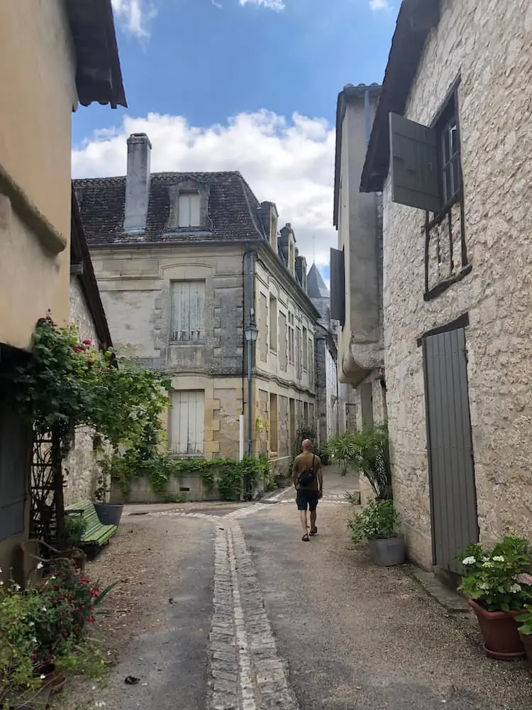 A man walks alone in a cobbled street with stone buildings on either side
