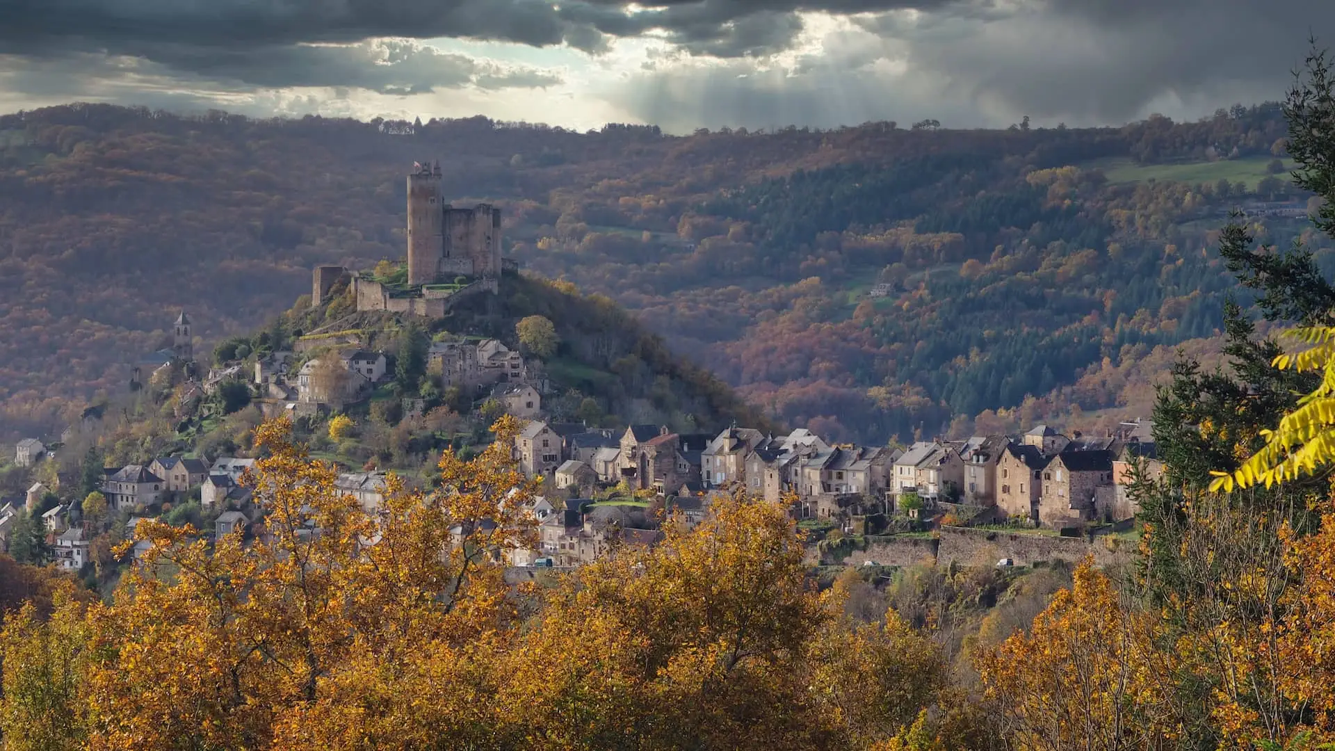 A row of houses lead to a castle on a hill, surrounded by countryside