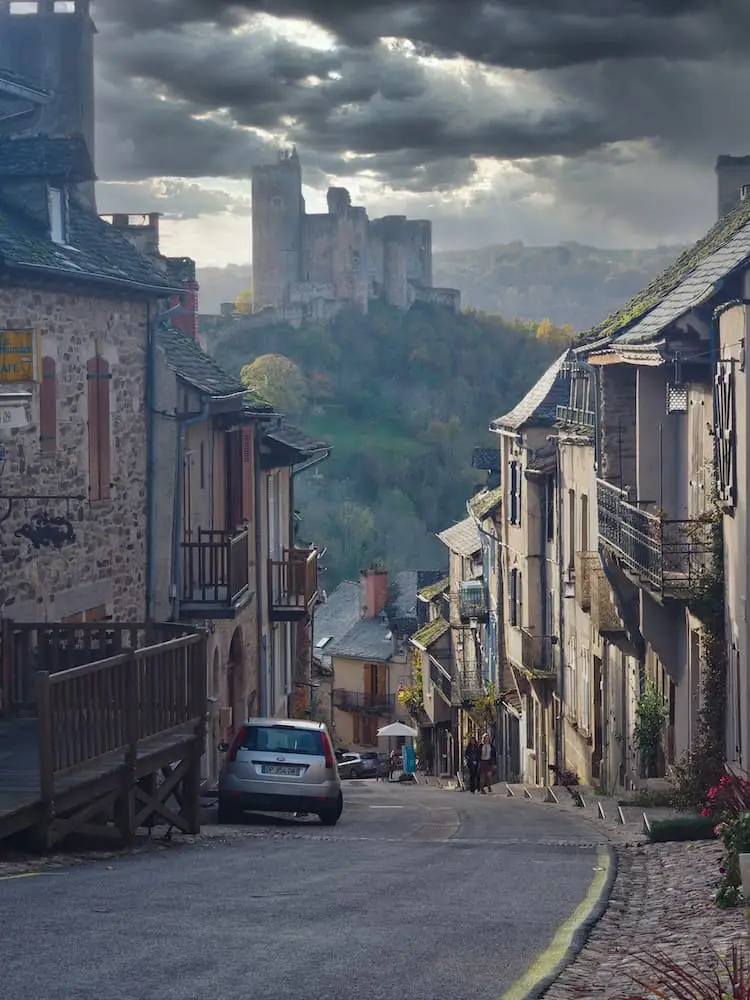 A street running downhill with a castle on a hill in the background