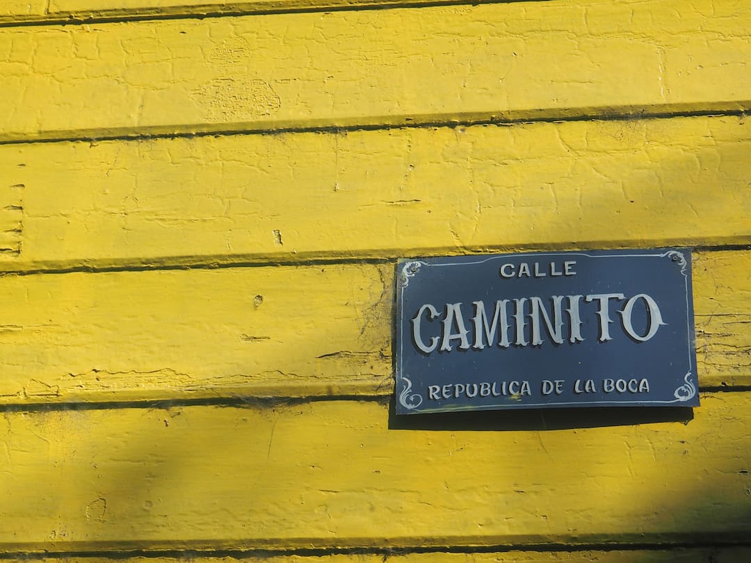 Yellow wooden panels with a grey street sign bottom right