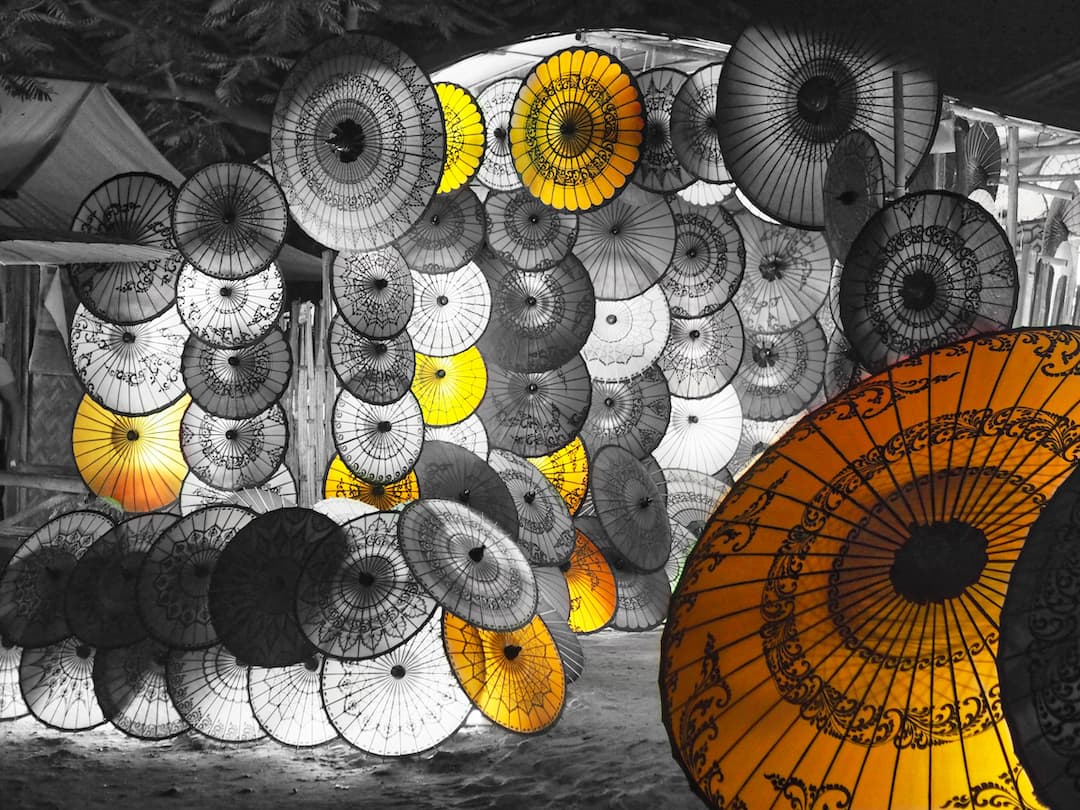 Monochrome image of lots of umbrellas stacked upon one another with the yellow ones appearing in colour