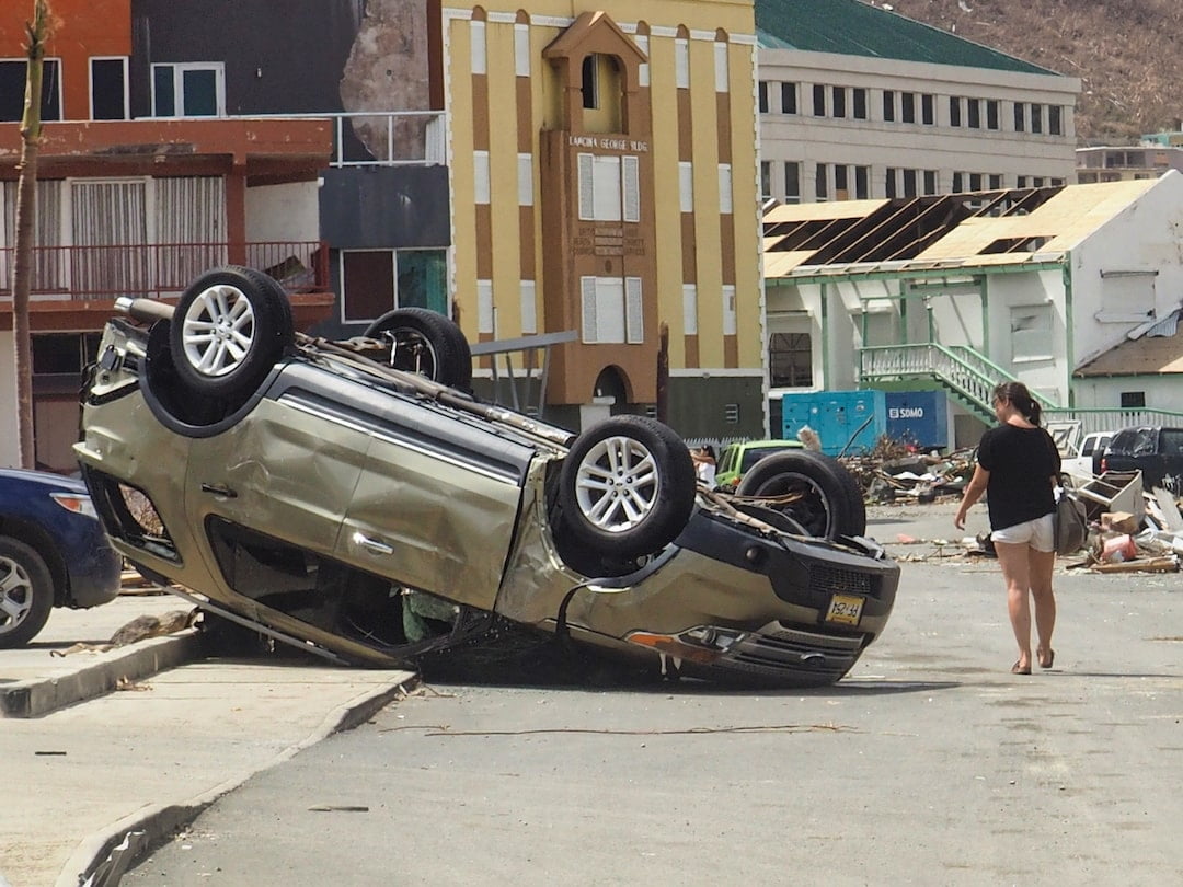 A woman walks past an overturned car