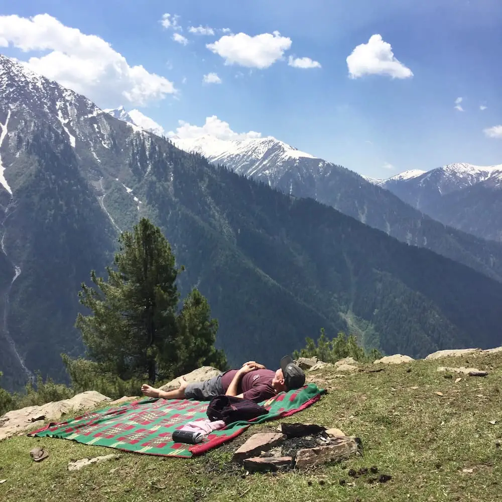 Kashmir Valley sleep Ian lies down on his back in a field overlooking mountains