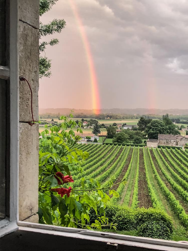 Looking out of an open window over a vineyard with a rainbow to the left