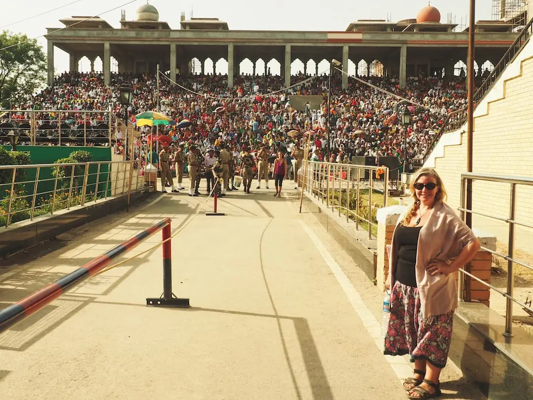 Nicky standing to the right of an entrance walkway with a grandstand in the background