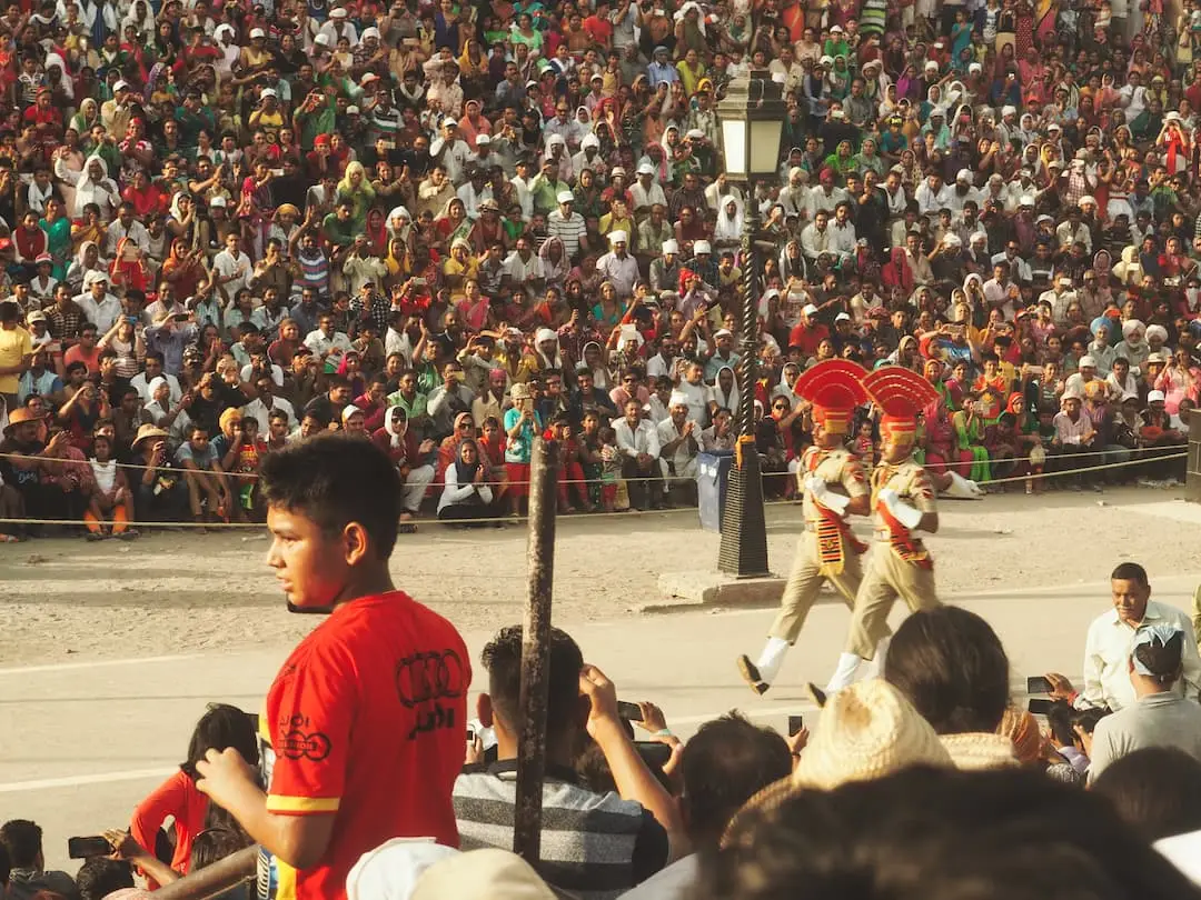 Two soldiers march in front of a seated crowd
