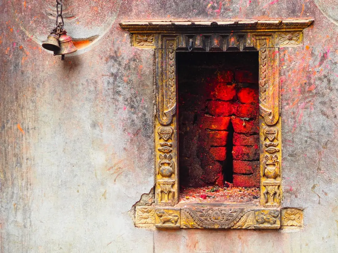 A window with a red brick inset and a bell to the left