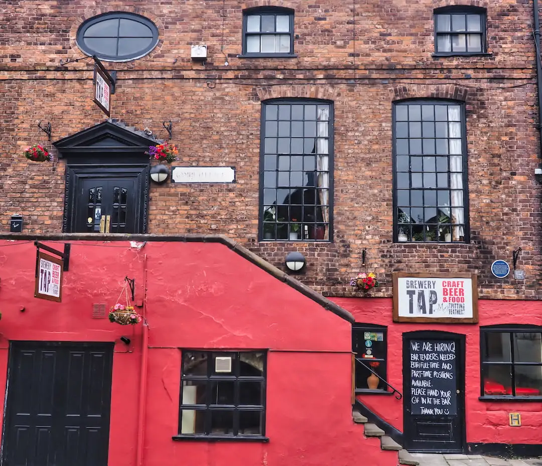 A red wall hides steps leading up to a door on a red bricked building