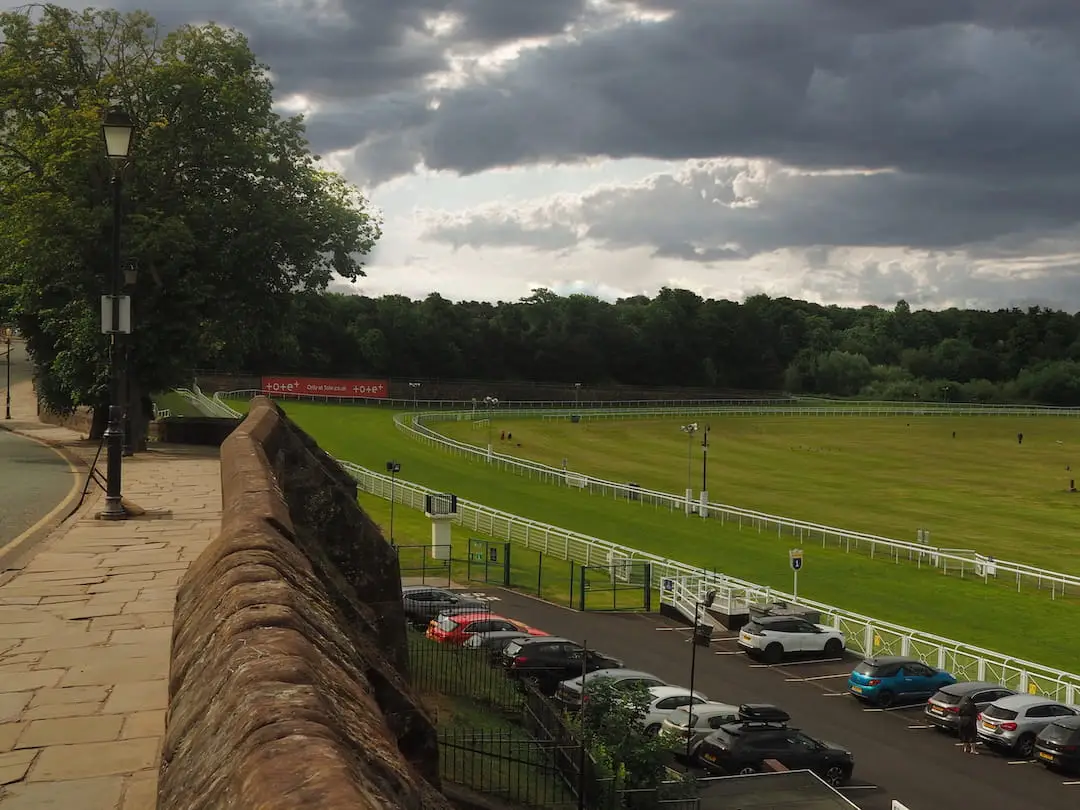 A path and a wall runs along  to the left overlooking a racecourse to the right