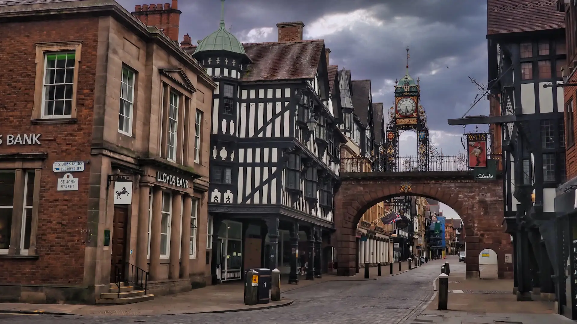 A row of ancient buildings with a sandstone bridge and a clock on top