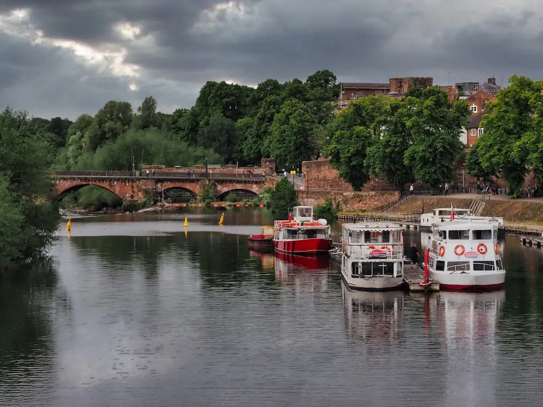 Two boats moored on a river with a stone bridge in the background