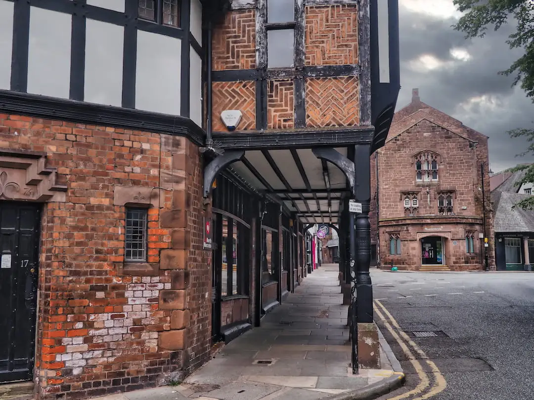 A sandstone buildings with an archway running between it and the road