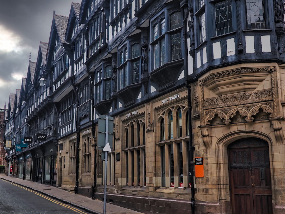 A row of sandstone buildings with black and white half-timbered facades
