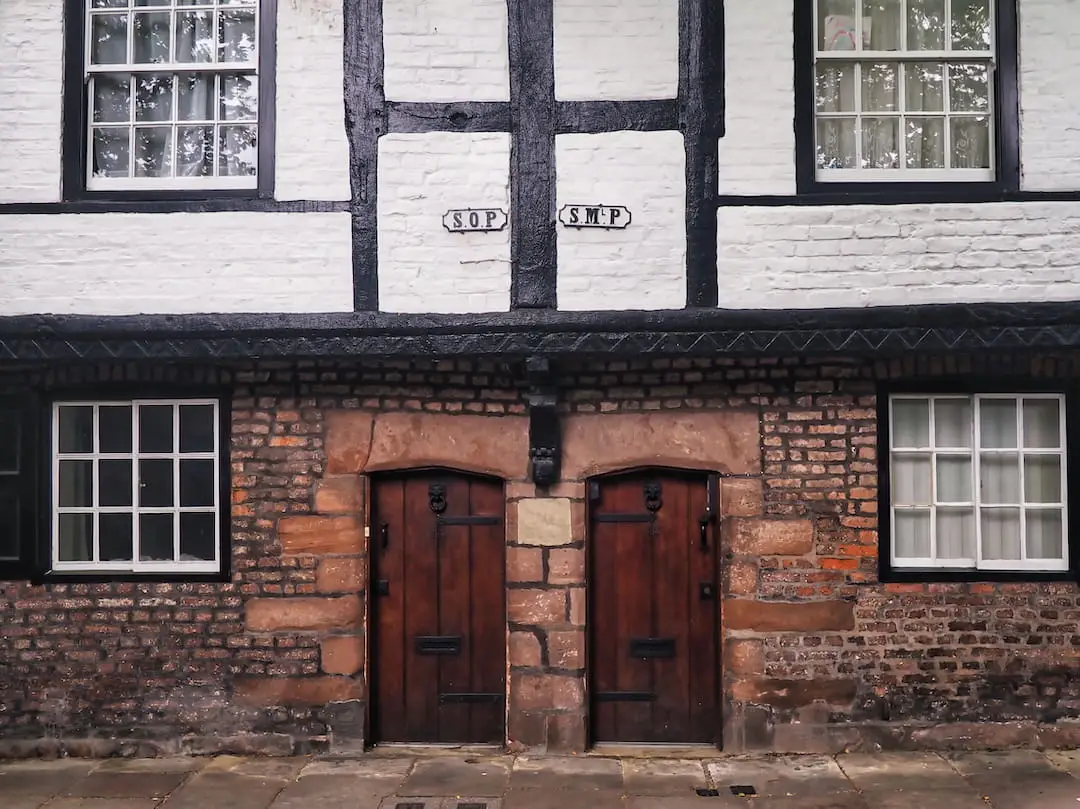 A brick building with black and white half-timbered facade on the first floor