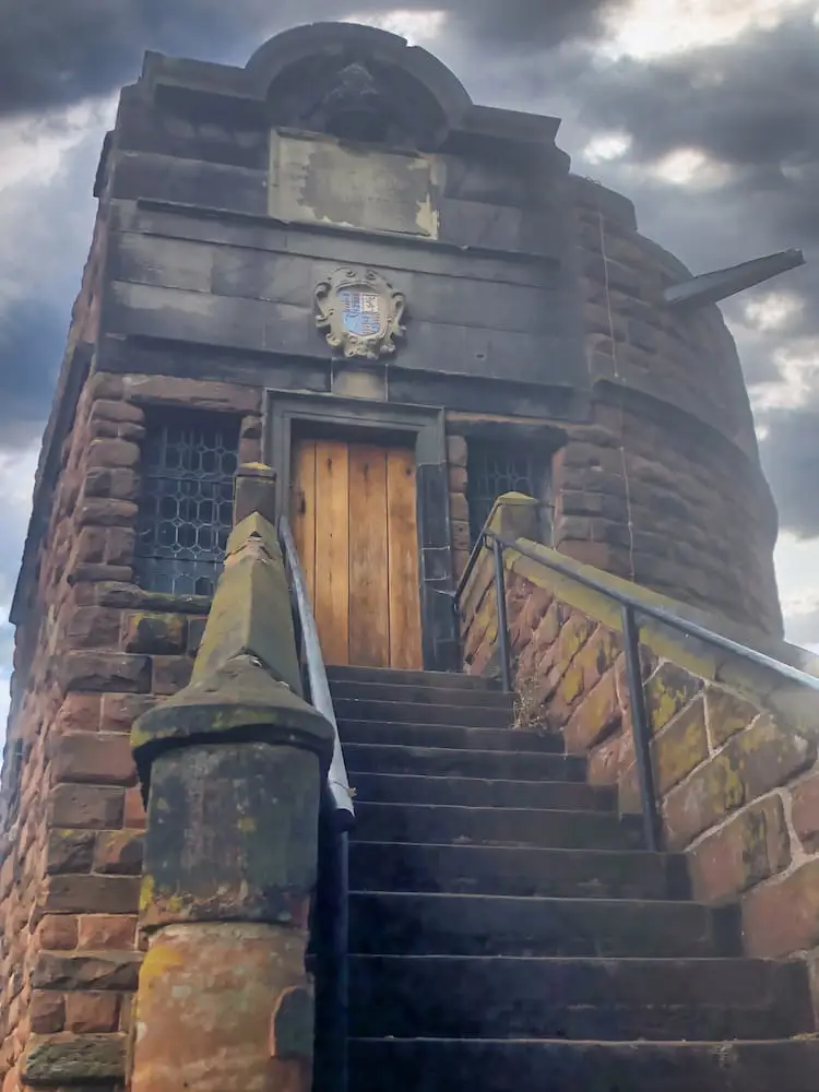 Stone steps lead up to a wooden door on a tower